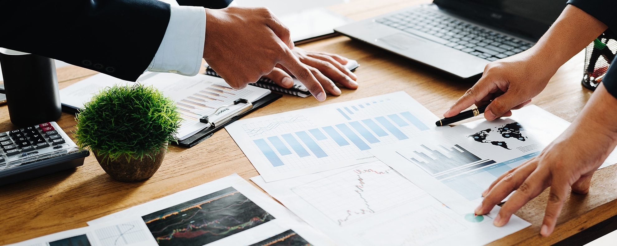 Closeup of professionals pointing at charts on desk